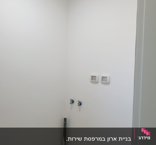 קיר לבן עם צינור וברזים מותקנים
